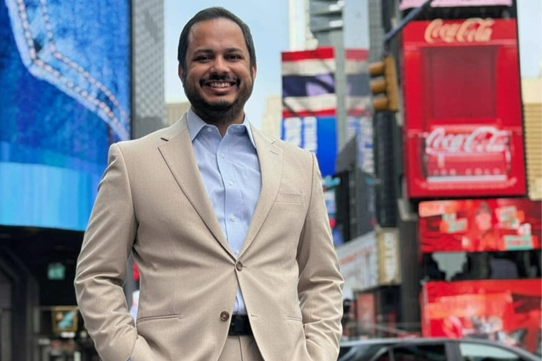 Minhaj Chowdhury headshot standing of front of Times Square billboards.